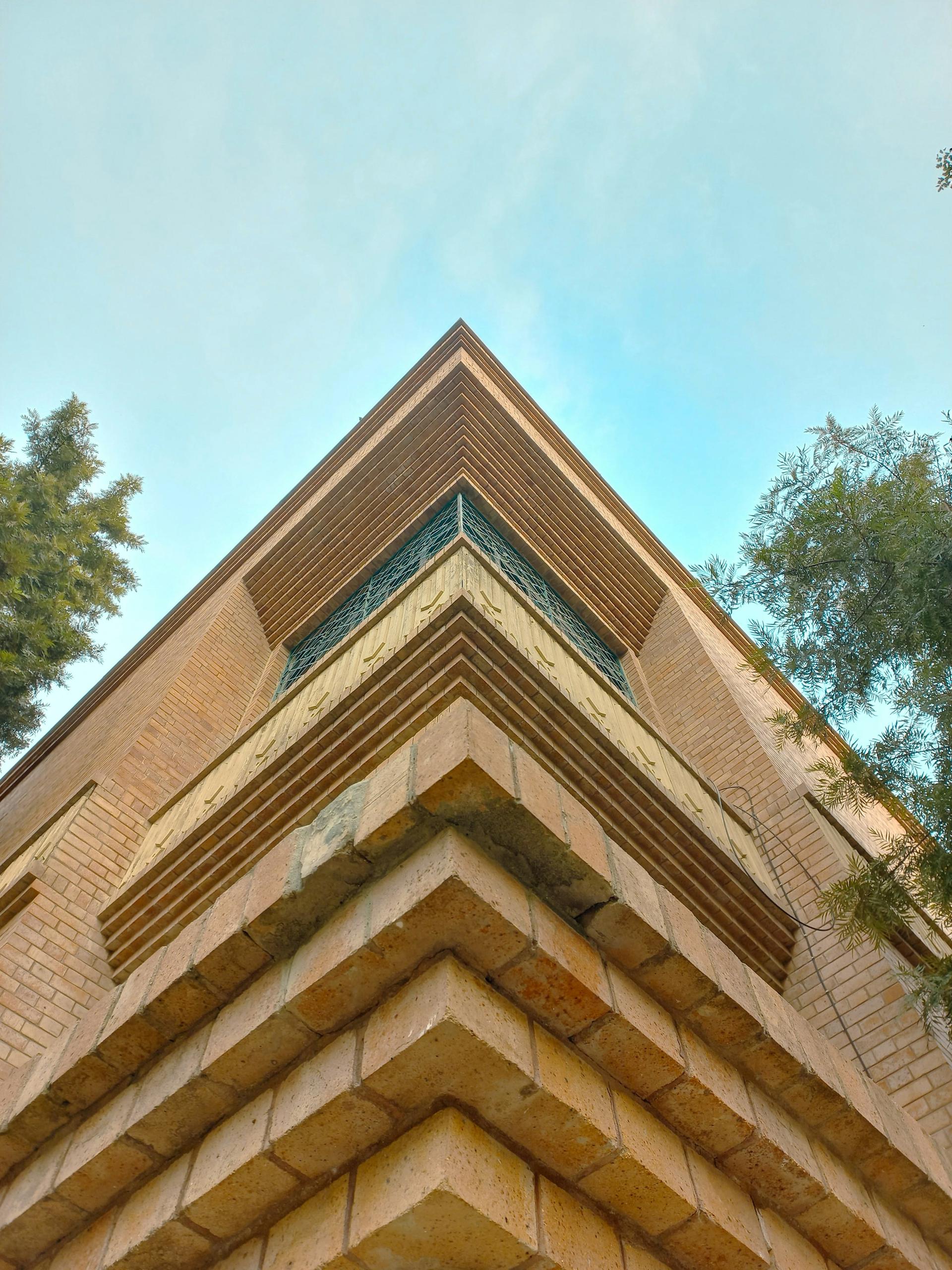 Low-angle view of a modern building with layered, angular balconies against a clear sky